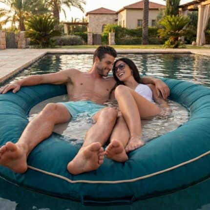 זוג מתחבק בתוך אבוב פוף צף טורקיז (Teal) AQua Ring בבריכת וילה יוקרתית