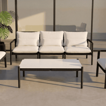 שולחן קפה מלבני MILOS בבזלת במרפסת מודרנית עם נוף עירוני וים בשקיעה, לצד כורסאות לאונג'.