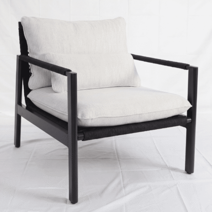 כורסת לאונג' מעוצבת MILOS במבט חזיתי-צדי. ריהוט גן יוקרתי של LÜMA המשלב אלומיניום שחור פחם, חבל סרוג וכריות מבד אולפין.