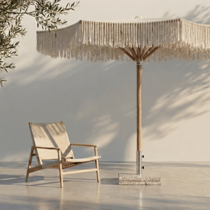 שמשיית TULUM מבית LÜMA מצלה על כורסת לאונג' בעיצוב מינימליסטי. משחקי צללים רכים של ענפי זית וחבלי השמשיה על קיר לבן.